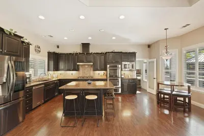 a kitchen with wooden cabinets and a island with bar stools at Oasis on the vine - Custom Luxury Resort Amenities in Lodi
