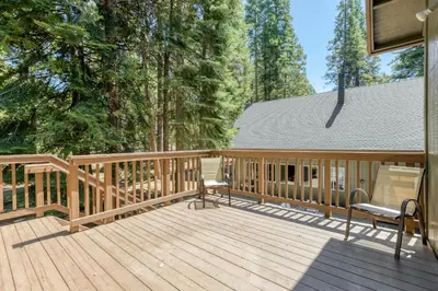 a large wooden deck with two chairs on it at Lazy Bear Lodge Rustic Luxe Villa with spa & gameroom in Shaver Lake