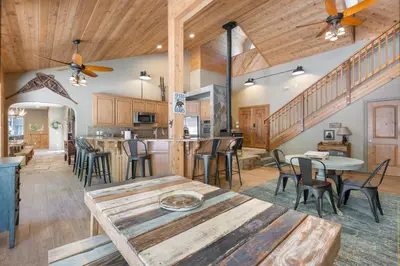 a kitchen and living room with wooden ceilings and tables at Lazy Bear Lodge Rustic Luxe Villa with spa & gameroom in Shaver Lake