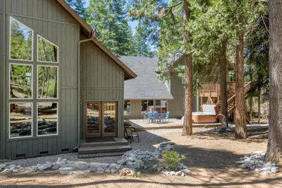 a green house with a patio and trees at Lazy Bear Lodge Rustic Luxe Villa with spa & gameroom in Shaver Lake