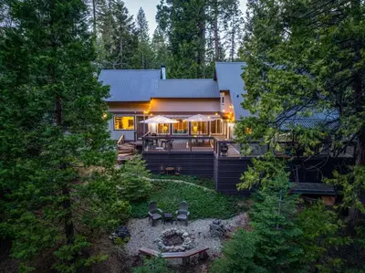 a house in the woods with a patio and a backyard at Cedar Horn- Serene Family Shaver Retreat in Shaver Lake