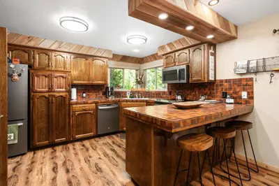 a kitchen with wooden cabinets and a island with stools at Cedar Horn- Serene Family Shaver Retreat in Shaver Lake