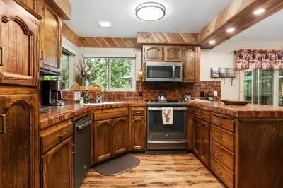 a kitchen with wooden cabinets and a stove top oven at Cedar Horn- Serene Family Shaver Retreat in Shaver Lake