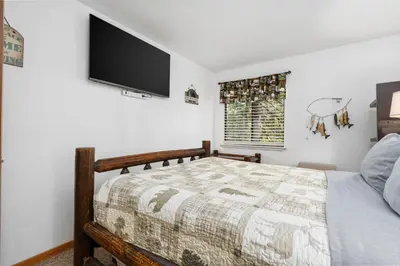 a bedroom with a bed and a flat screen tv at Kamp Kokanee-Updated Condo Near Spa Sauna in Shaver Lake