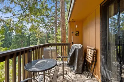a balcony with a table and chairs on a porch at Kamp Kokanee-Updated Condo Near Spa Sauna in Shaver Lake