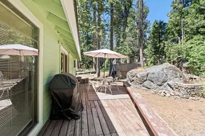 a porch with a table and umbrella on a house at Happy Bear- Family & Pet Friendly in Shaver Lake