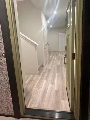 a hallway with a door open to a room with wood floors at A modern retreat and Gateway to Yosemite in Merced
