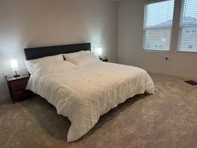 a bedroom with a large white bed with two lamps at A modern retreat and Gateway to Yosemite in Merced