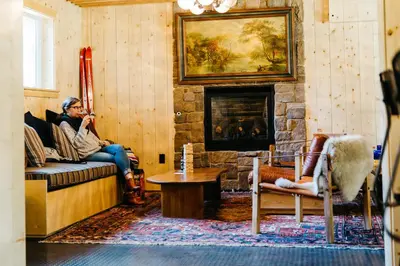 a woman sitting on a couch in a living room with a fireplace at The Coachman Hotel in South Lake Tahoe