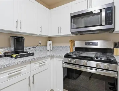 a kitchen with white cabinets and a stove and a microwave at Casa Cortez C in Visalia
