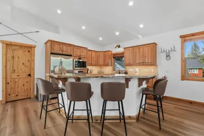 a kitchen with wooden cabinets and a island with bar stools at Evergreen Getaway Pet Friendly in SLT w Hot Tub in South Lake Tahoe