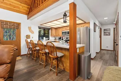 a kitchen with wooden cabinets and a bar with chairs at Kokanee Hideaway-Family Friendly 5BR Epic Game Room in Shaver Lake