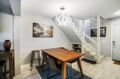 a dining room with a table and a staircase at Guest Favorite Spacious Remodeled 2 Bdrm 2 Ba Mountain Views in Mammoth Lakes