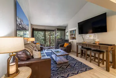 a living room with a couch and a desk with a television at Guest Favorite Spacious Remodeled 2 Bdrm 2 Ba Mountain Views in Mammoth Lakes