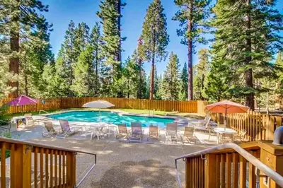 a swimming pool with chairs and umbrellas in a yard at Cozy Kings Run Condo in Tahoe Vista