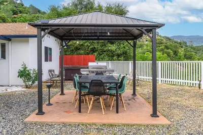 a pavilion with a table and chairs under it at Amazing Views Hot Tub-Games-Fire pit 6BR Sleeps 20 in Oakhurst