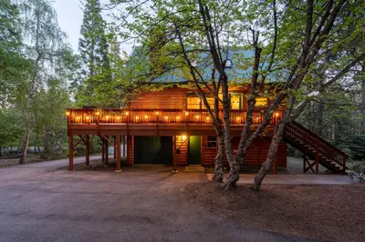 a house with a deck with lights on it at Happy Trails-Family Style Log Home Winter Escape in Shaver Lake