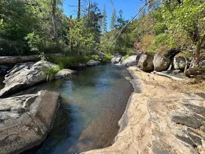 a stream of water with rocks and trees at Cedar Springs Retreats in North Fork