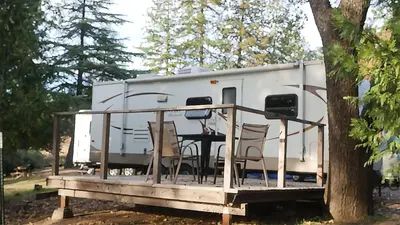a white trailer with a table and chairs on a deck at Cedar Springs Retreats in North Fork