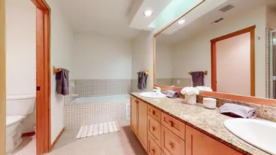 a bathroom with two sinks and a mirror and a tub at Snowcreek V #819 condo in Mammoth Lakes