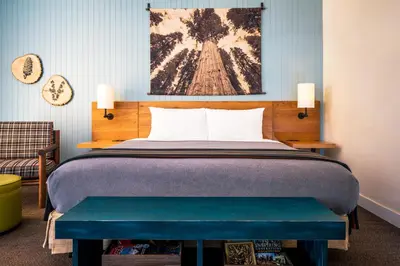 a bedroom with a bed with a bench next to it at Rush Creek Lodge at Yosemite in Groveland