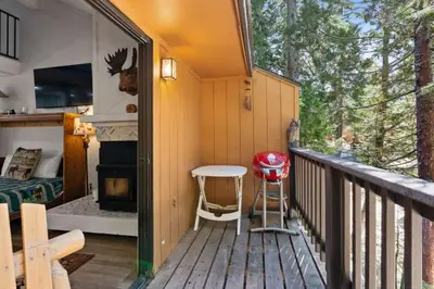 a small deck with a table and a fireplace at Wilderness Hideaway-Across from the pool & spa in Shaver Lake