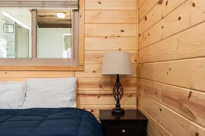 a bedroom with wooden walls and a bed with a lamp at Blue Meadow-Family Pet Friendly & near the lake in Shaver Lake