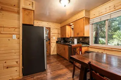 a kitchen with a black refrigerator and a wooden floor at Blue Meadow-Family Pet Friendly & near the lake in Shaver Lake