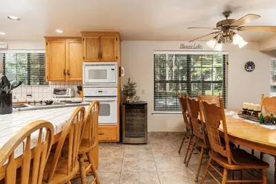 a kitchen with a table and chairs and a ceiling fan at Rustic Pines- Family Fun Game Cabin in East Village in Shaver Lake