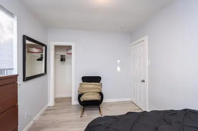 a bedroom with a black chair and a white wall at 2 Bedroom Home Near Downtown Zoo Golf Pet-Friendly and Fenced in Sacramento