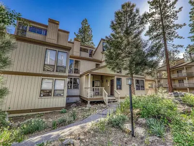 a large house with a porch and a tree at Kingswood Pines in Kings Beach