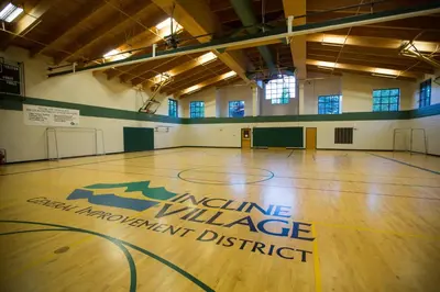 a gym with a basketball court with an insurance village management district sign on the floor at The Treetop Retreat in Incline Village