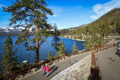 two people walking along a path next to a lake at The Treetop Retreat in Incline Village
