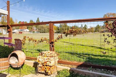 a garden with a fence with a tree and a field at Vintage Vine House in Murphys