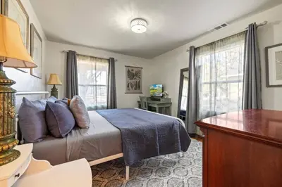 a bedroom with a bed and a desk and windows at Vintage Vine House in Murphys