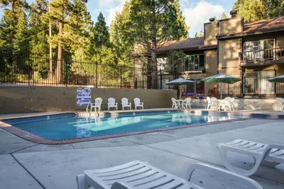 a swimming pool with chairs and umbrellas next to a house at Fireside at Tahoe City in Tahoe City
