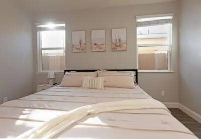 a large white bed in a bedroom with two windows at New Modern 3bed in North Merced 5 Star hosts in Merced