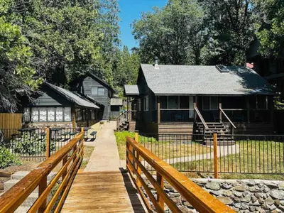 a log cabin with a fence and a wooden walkway at Boat Dock - Lake Front - Dog Friendly - Sleeps 23 in Bass Lake