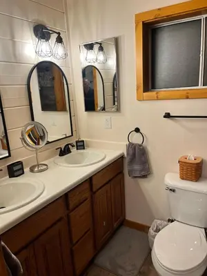 a bathroom with a toilet and two sinks and a mirror at Twain Harte Cozy cabin downtown in Twain Harte