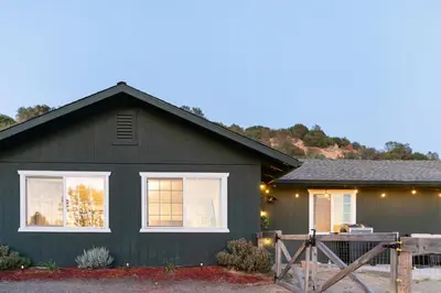 a black house with a fence in front of it at Cold Plunge, Hot Tub, Firepit, BBQ, Pet-Friendly, Sunset Views near Yosemite in Coarsegold