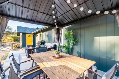 an outdoor patio with a wooden table and chairs at Cold Plunge, Hot Tub, Firepit, BBQ, Pet-Friendly, Sunset Views near Yosemite in Coarsegold