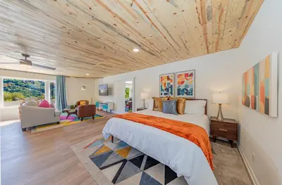 a bedroom with a large bed with a wooden ceiling at Skyfalls Retreat Mid-Century Guesthouse near Yosemite in Oakhurst