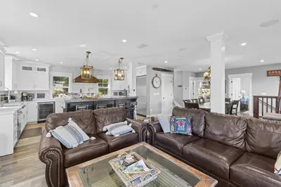a living room with a brown leather couch and a kitchen at Lakeview Luxury Retreat with Hot Tub and Game Room in Carnelian Bay
