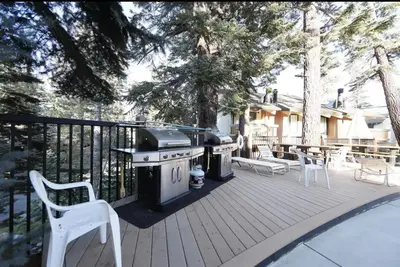 a grill on a deck with chairs and trees at Discovery Four 109 in Mammoth Lakes