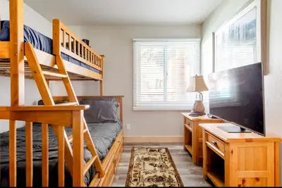 a bedroom with a bunk bed and a desk with a television at Mammoth Creek 29 in Mammoth Lakes