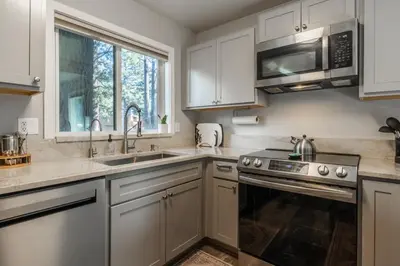 a kitchen with white cabinets and a sink and a microwave at Wildflower 65 in Mammoth Lakes