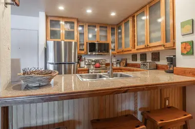 a kitchen with wooden cabinets and a stainless steel refrigerator at Summit 33 in Mammoth Lakes