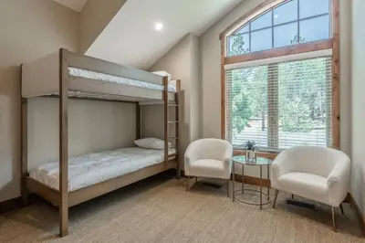 a bedroom with a bunk bed and two chairs and a window at Stonegate 11 in Mammoth Lakes