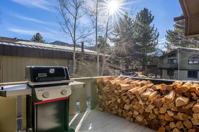 a grill on a deck next to a pile of logs at Chateau De Montagne 4 in Mammoth Lakes