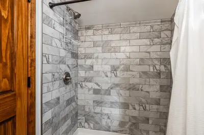 a bathroom with a shower with a stone wall at Winterset 20 in Mammoth Lakes